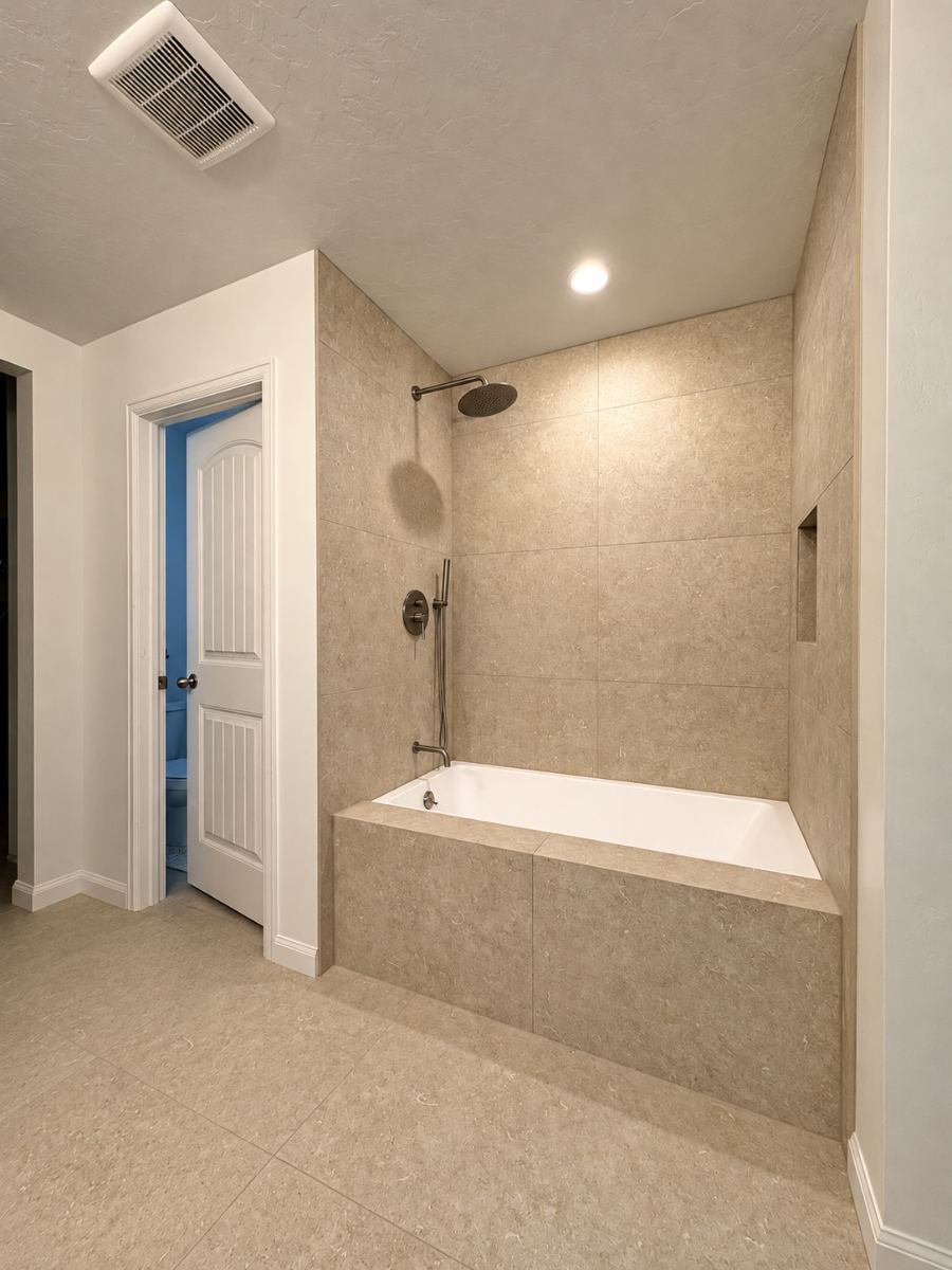 Tiled tub-shower combo with rain head and niche after remodel