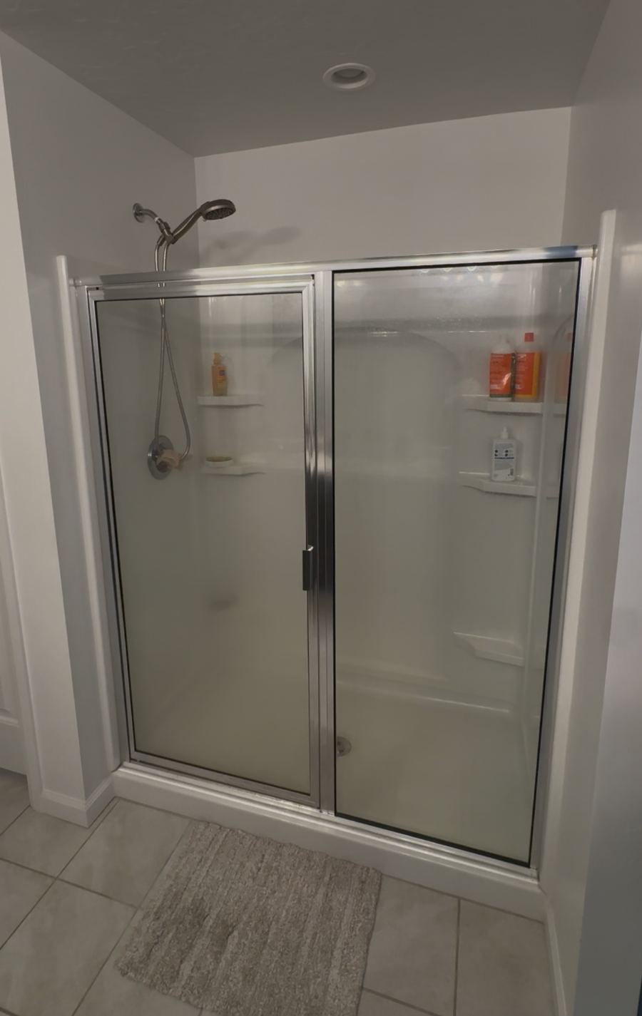 Fiberglass shower stall with framed glass doors before remodel