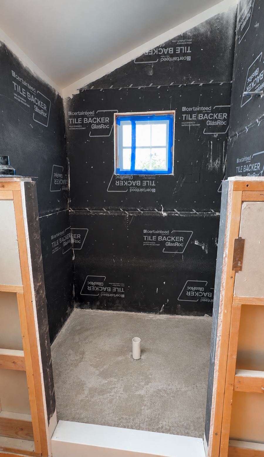 Shower alcove at tile-backer stage with drain rough-in